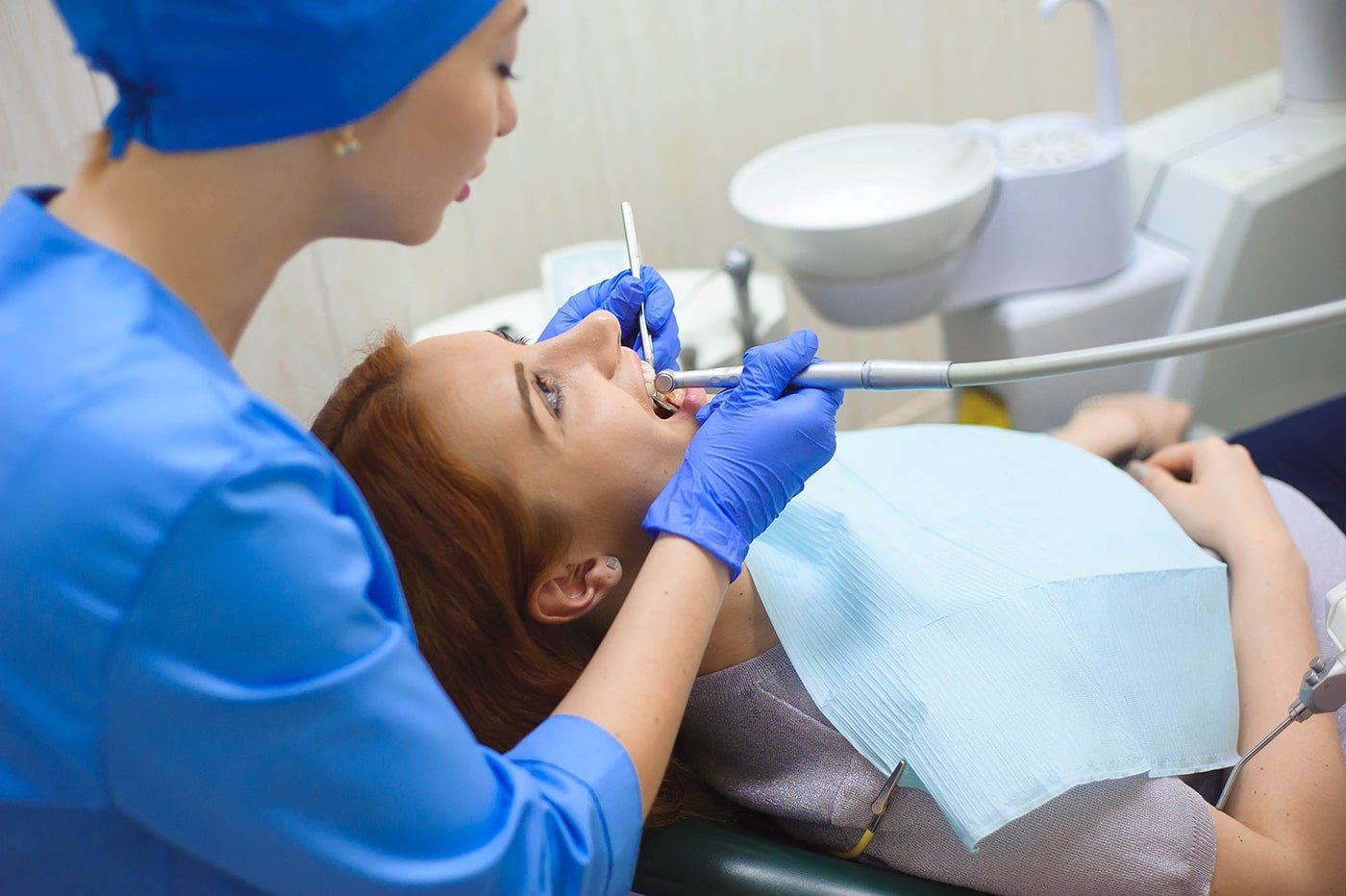 doctor-uniform-checking-up-female-patient-s-teeth-dental-clinic-min